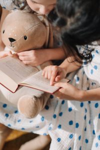 little girls with a stuffed bunny trying to read a book